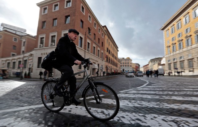French Cardinal Barbarin rides his bicycle as he arrives for a meeting in the Vatican's synod hall